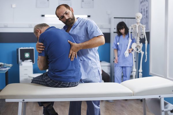 Chiropractor provides aid to patient Osteopathic nurse gently extends spine of elderly patient with injury as part of physiotherapy. Chiropractor provides aid to gentleman experiencing back pains, aiding in physical recovery.